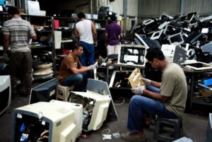 Bacs contenant des ordinateurs, écrans et périphériques triés dans un centre de recyclage informatique.